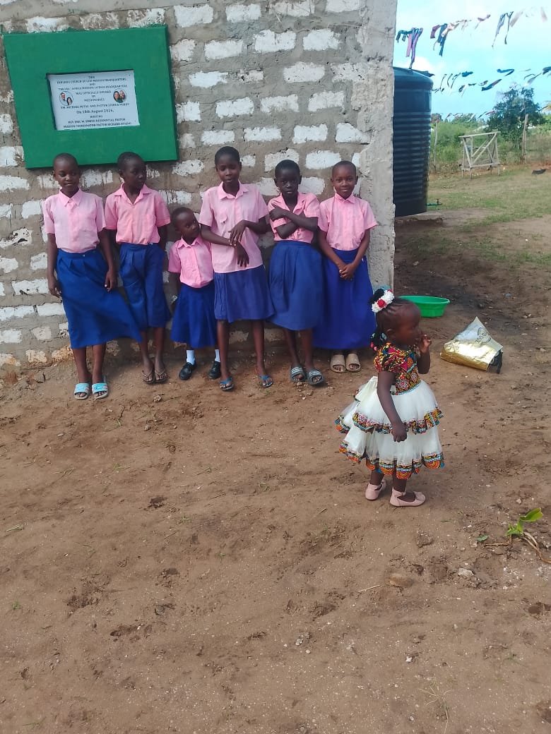 Children in pink uniforms at the headquarters plaque